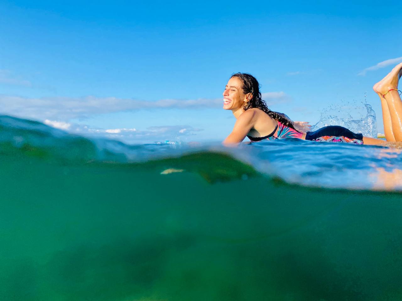 Soukaina smiling on her surfboard in Taghazout, Morocco - Surf Treasure Morocco surf camp