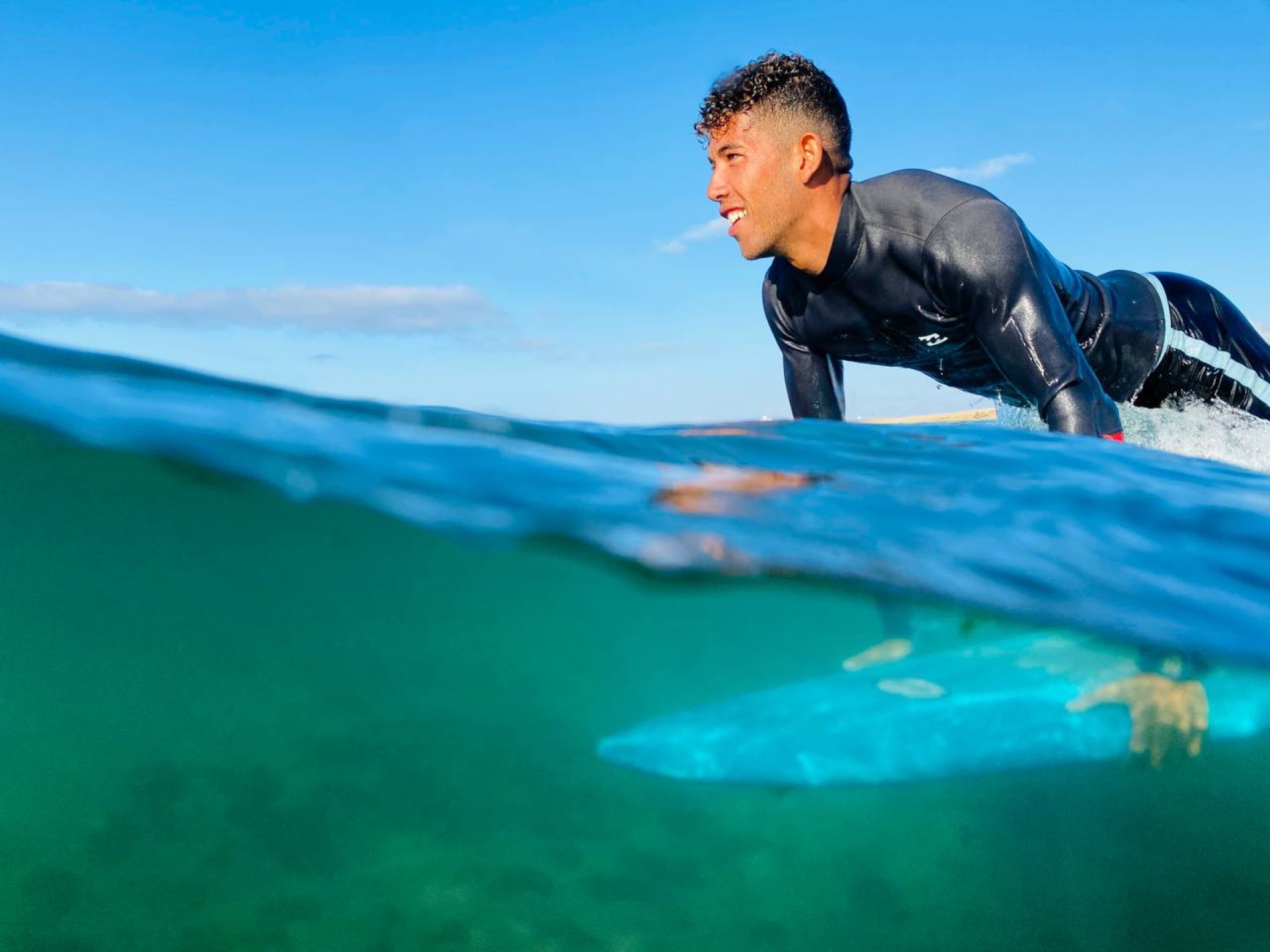 Surfer paddling in clear blue water at Taghazout