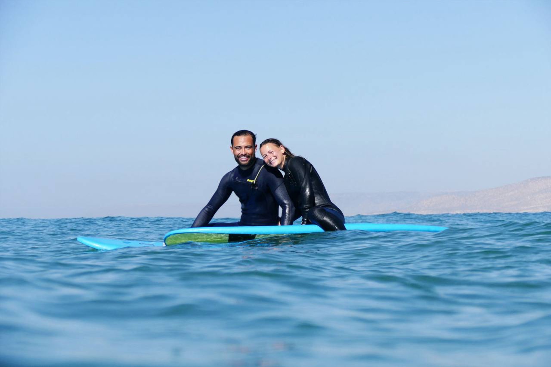 Couple smiling on surfboards in the ocean