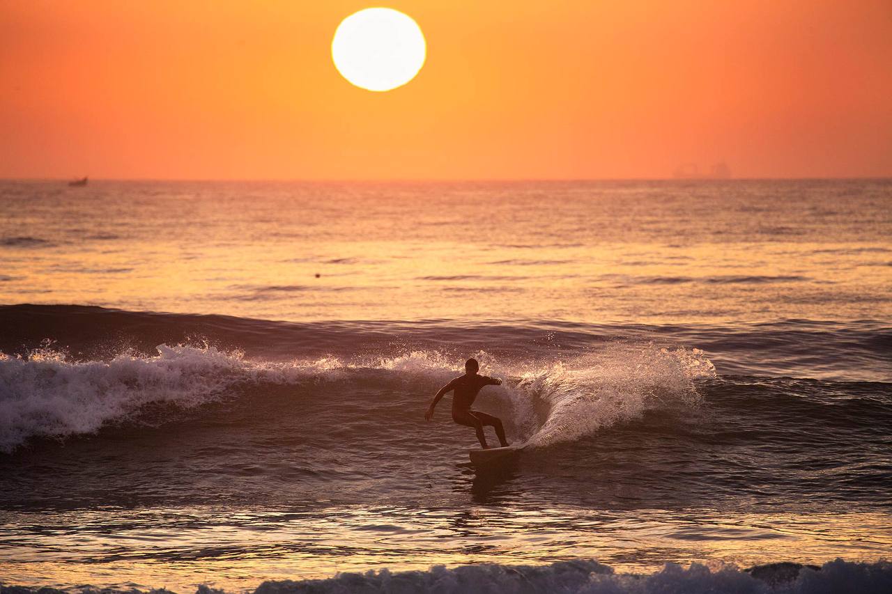 Surfer carving a sunset wave at Banana Beach