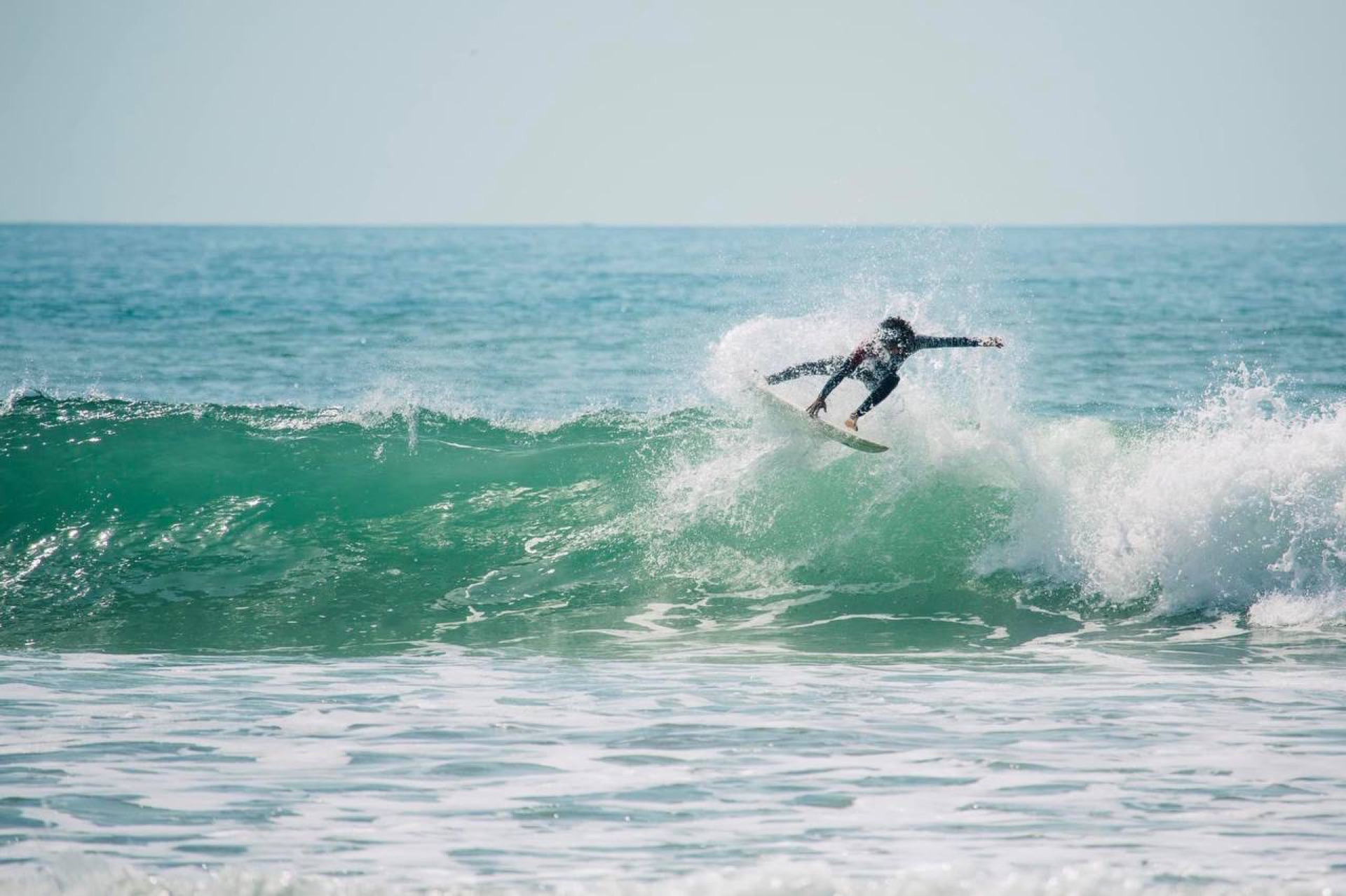 Surfer carving a turquoise wave at Banana Point