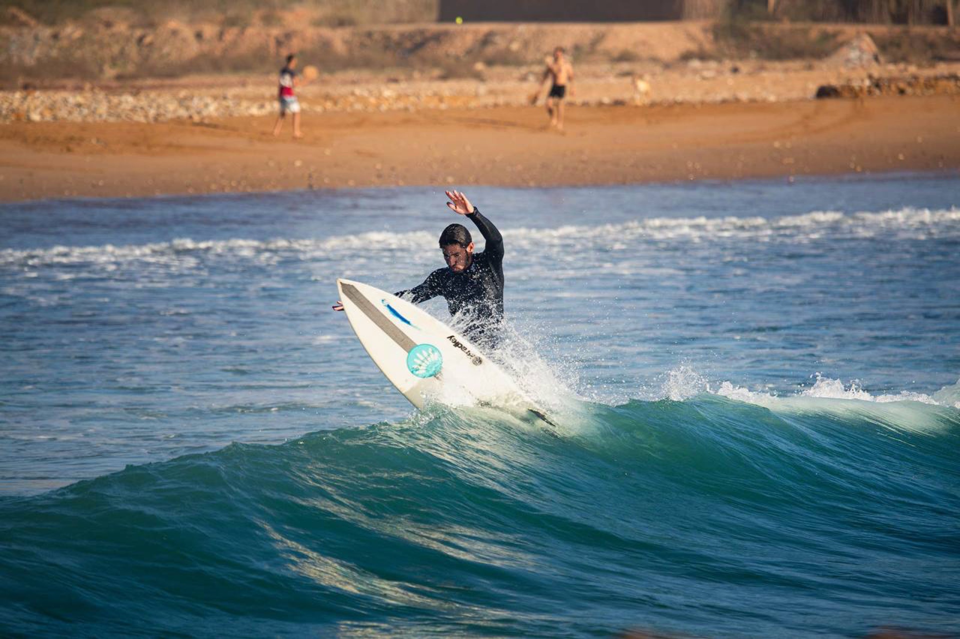 Surfer riding wave with beach in background at Banana Point
